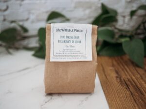 Life Without Plastic's Pure Baking Soda in a brown paper packet with a product and safety label attached against a wooden backdrop..